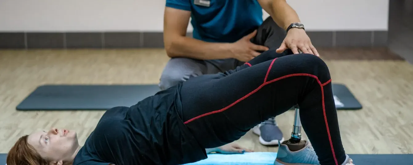 A practitioner supervising a patient performing a bridge exercise on a mat